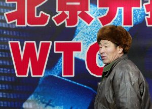 (FILES) This file photo taken on December 9, 2002 shows a man walking past an advertising billboard relating to China's World Trade Organisation (WTO) entry in Beijing. / AFP PHOTO / FREDERIC J. BROWN